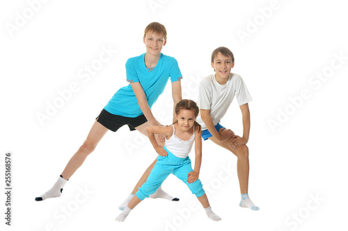 Portrait of two young boys brothers and little sister exercising isolated on white background