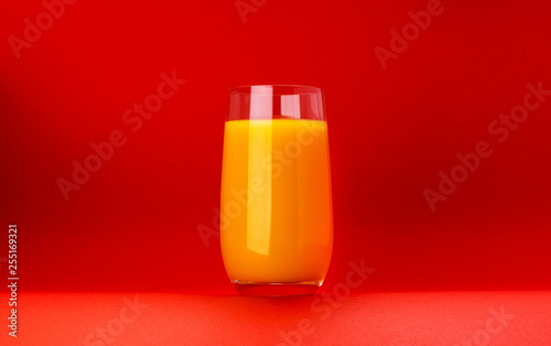 Glass of orange juice isolated on red background with copy space