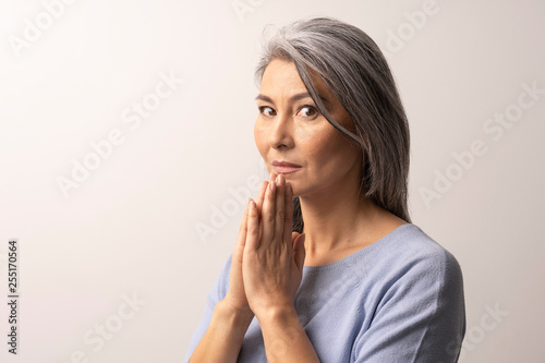 Mature Asian woman praying on white background