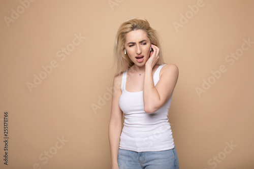 Portrait of a cheerful young woman in headphones listening to music isolated over beige background 