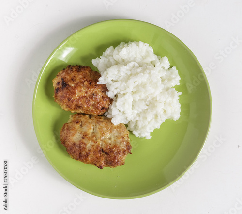 Cutlets and boiled rice on a plate on a white background.