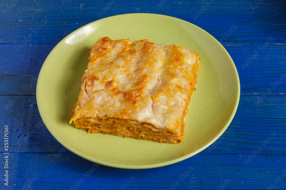 A piece of lasagna on a plate on the table.