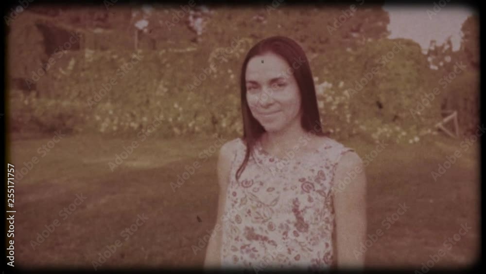 Family video archive. Retro camera 8 mm. Old film. Young attractive woman having fun in the green garden. Portrait of a smiling brunette with dimpled cheeks against a green park. Pretty girl in summer