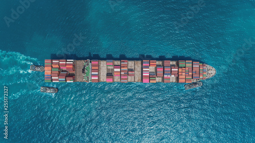 Aerial top view Large Container ship drag by three Tug boat at sea port for unload container to warehouse for logistics, import export, shipping or transportation.