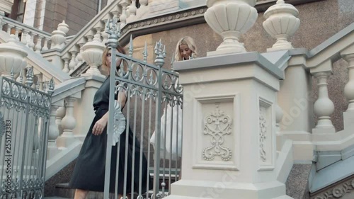 Two models of the girl sit on the gothic railing.