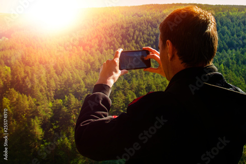 A man takes pictures on the phone natural landscape. nature, travel, tourism, recreation.