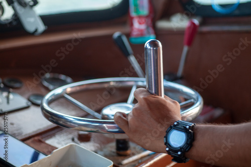 man's hand on the steering wheel in the clock controls the sea boat