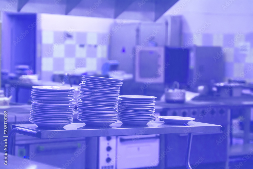 Fototapeta premium interior of the kitchen, a stack of clean plates in the kitchen are on the tables. in the background of the stove