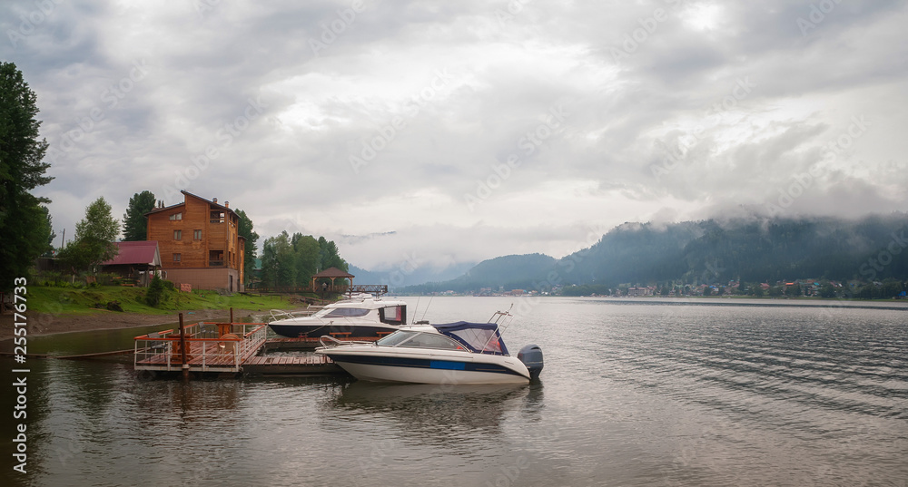summer landscape on a mountain lake. fog over the forest and mountains.  glade two small boats near the shore side view