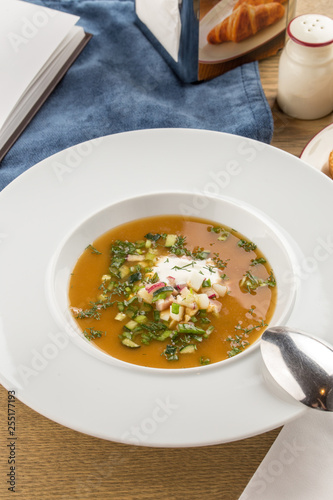 Summer cold soup okroshka with radish, cucumber and dill on wooden table