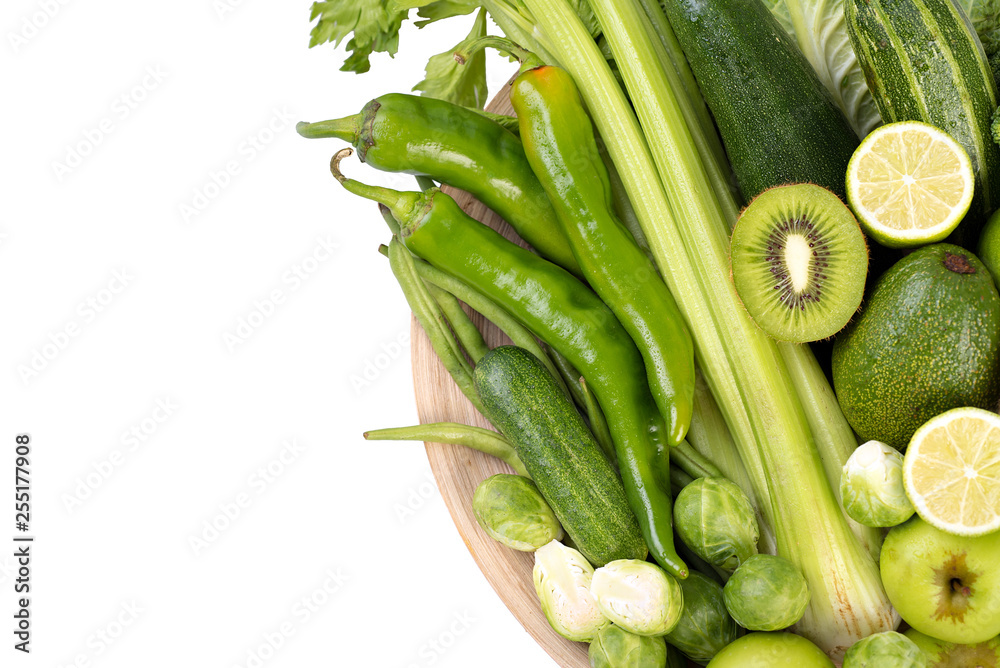 Green vegetables on wooden plate on white background