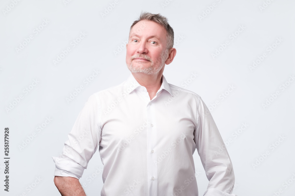 Smiling senior man in white shirt standing and smiling at camera feeling good Smiling senior man in white shirt standing and smiling at camera feeling good
