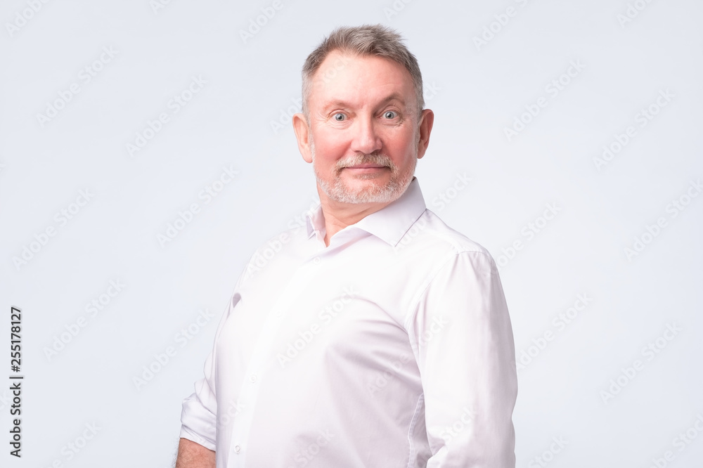 Smiling senior man in white shirt standing and smiling at camera feeling good Smiling senior man in white shirt standing and smiling at camera feeling good