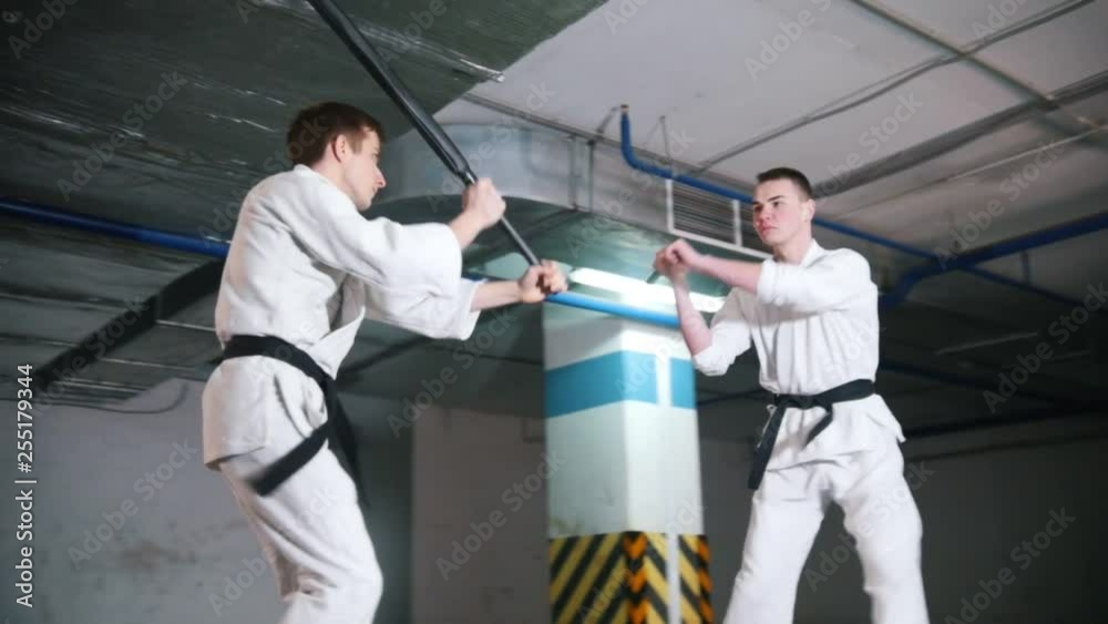 Two men in kimono training kendo on a parking lot. Sword fight Two men in kimono training kendo on a parking lot. Sword fight