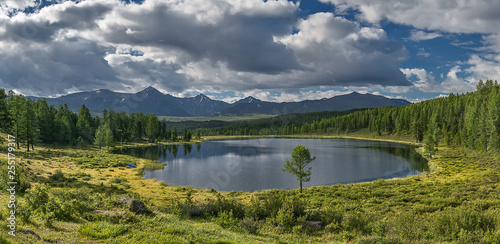 tourism and travel  summer landscape in Altai mountains  round small lake. white clouds in the blue sky are reflected in the water.