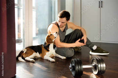 The guy goes in for sports at home with a dog. Exercises for a healthy lifestyle.