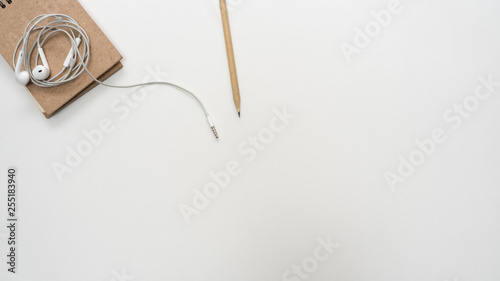 Office desk table with notebook and earphone close up Top view copy space