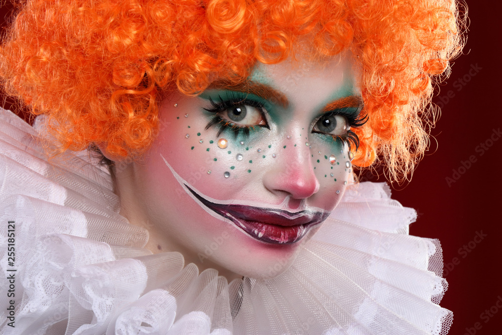 Cute red-haired clown.Girl in bright clown makeup. Close up. Stock Photo