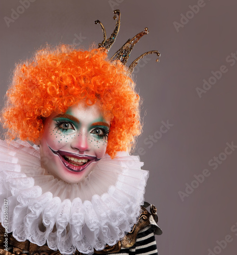 Cute red-haired clown.Girl in bright clown makeup. 