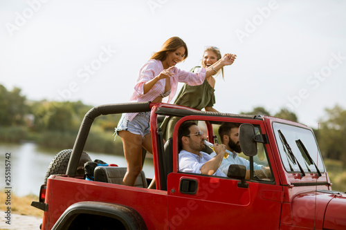 Group of happy young friends having fun in convertible car during summer vacation