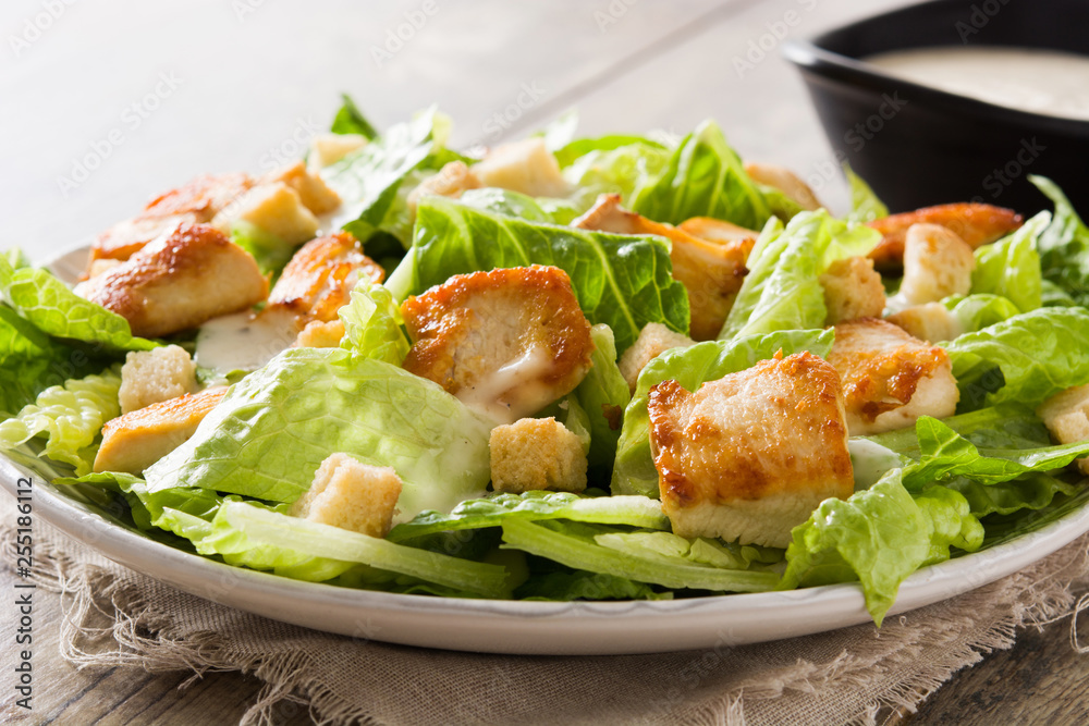 Caesar salad with lettuce,chicken and croutons on wooden table.. Close up Caesar salad with lettuce,chicken and croutons on wooden table.. Close up