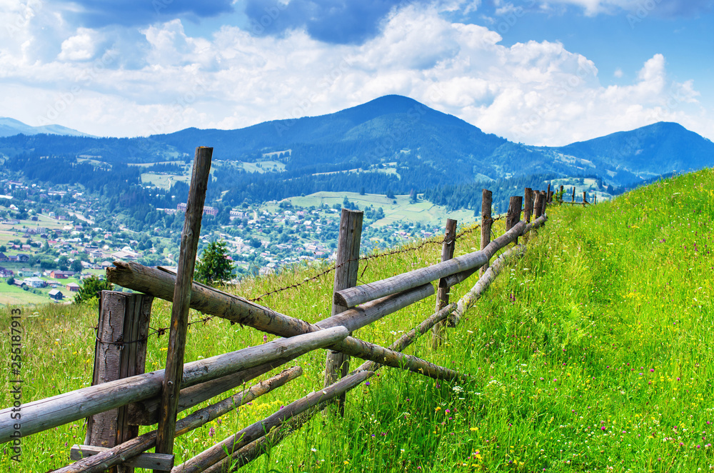wooden fence with barbed wire on a meadow in the mountains