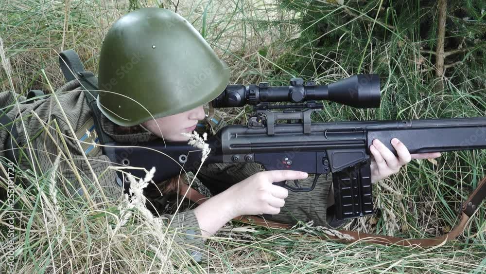 Close Female soldier in meadow aims target and duck