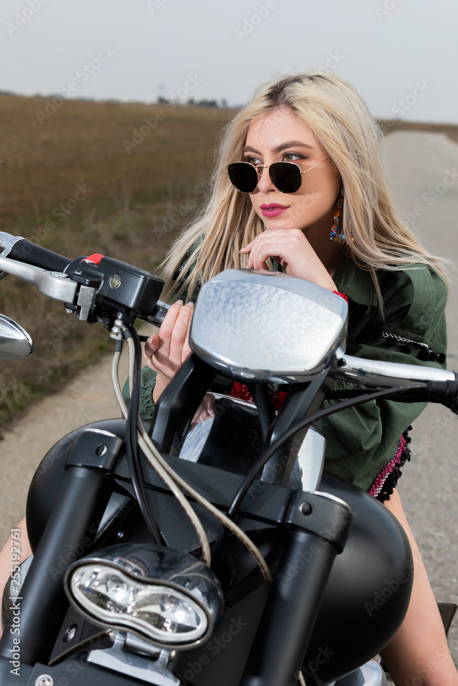 A beautiful young woman sitting on a black and chrome motorbike