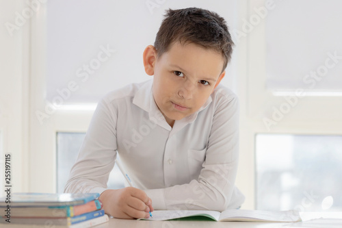 the boy learns lessons writing in a notebook at the Windows background.schoolboy doing homework