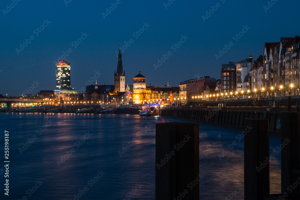 A picture of the center of Dusseldorf in Germany during the evening. The sun went down and only blue sky is above the city. 