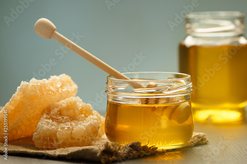 Honey background. Sweet honey in the comb, glass jar. On wooden background..