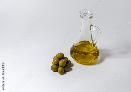 A small jug with oil and some olives on a white background-image