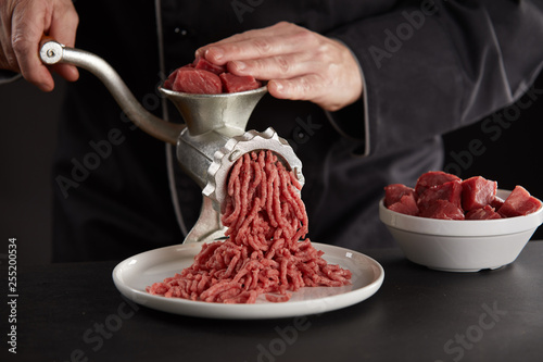 Man making minced meat with manual grinder photo