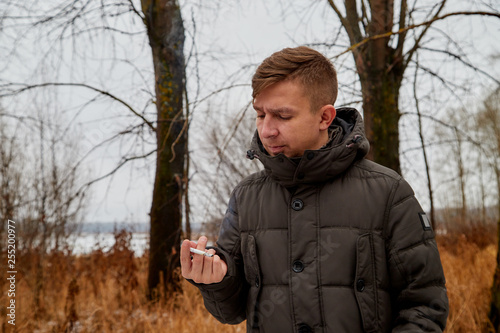 Ordinary man in an autumn coat smoking a cigarette in the park