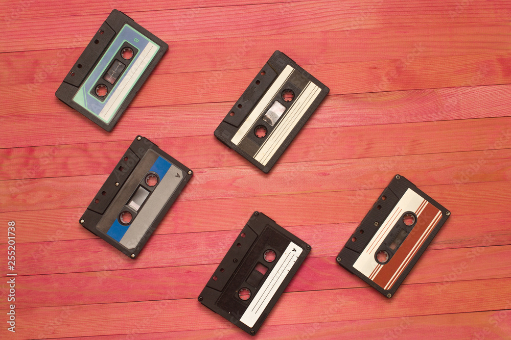 Fototapeta premium audio cassettes tape lay on pink wooden plank