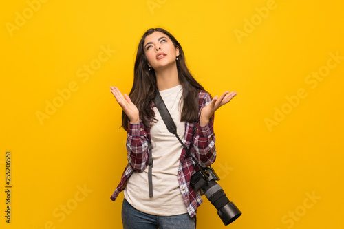 Photographer teenager girl over yellow wall frustrated by a bad situation
