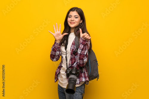 Photographer teenager girl over yellow wall counting six with fingers