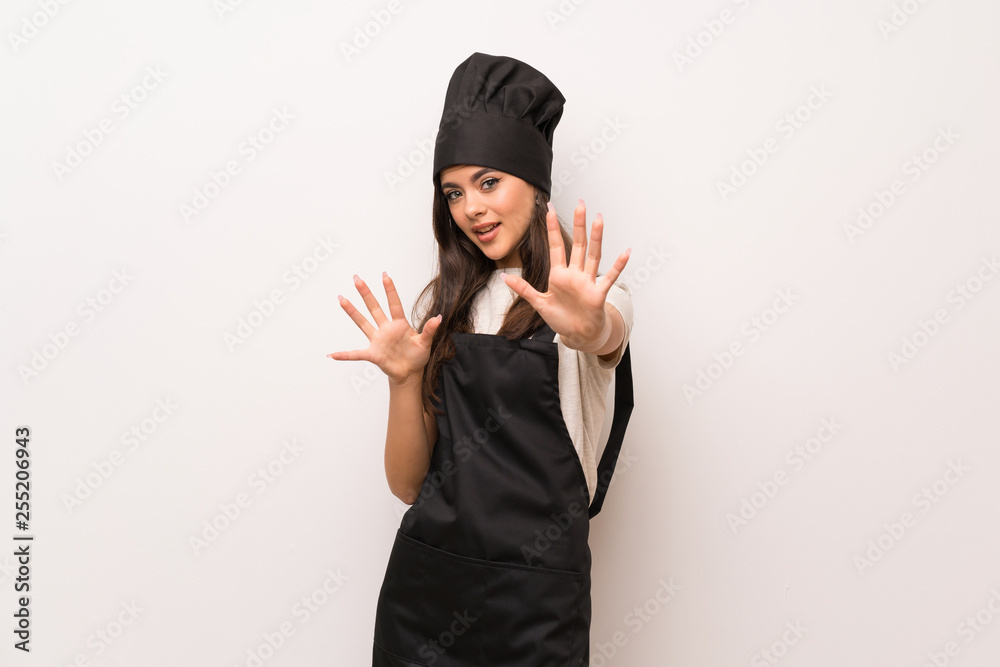 Teenager chef over white wall nervous and scared stretching hands to the front Teenager chef over white wall nervous and scared stretching hands to the front