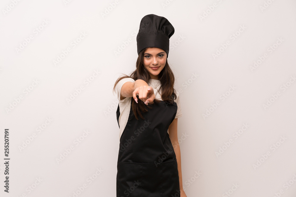 Teenager chef  over white wall points finger at you with a confident expression