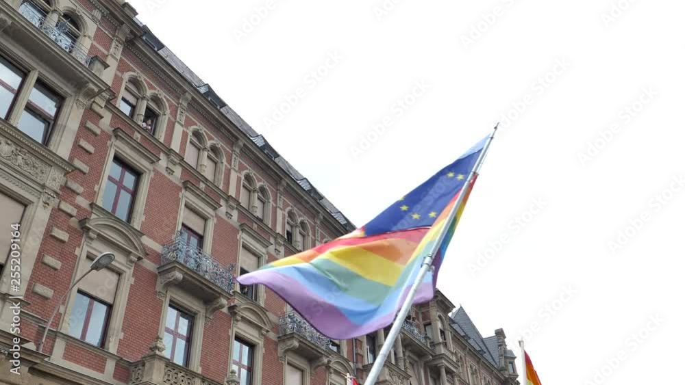 Waving United Nations, European union, French National and German national flags waving on the same flagpole with LGBT rainbow flag at annual pride march demonstration Waving United Nations, European union, French National and German national flags waving on the same flagpole with LGBT rainbow flag at annual pride march demonstration