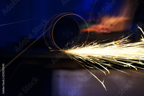 Metal grinding on steel pipe with flash of sparks close up