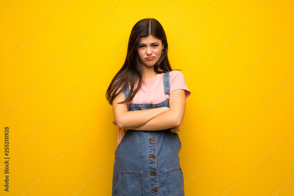 Teenager girl over yellow wall feeling upset Teenager girl over yellow wall feeling upset