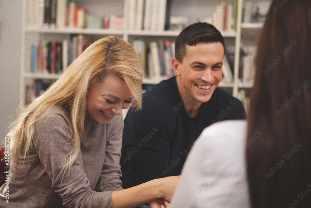 Happy college friends laughing joyfully, talking at the campus library. Cheerful male student having fun with his friends at school. Communication, lifestyle, education concept