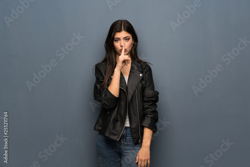 Teenager girl over grey wall showing a sign of silence gesture putting finger in mouth © luismolinero