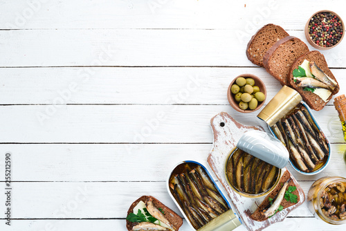 Sprats with oil in a jar. On a white wooden background. top view. Free copy space.