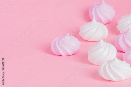 White and pink twisted meringues on pink background. French dessert prepared from whipped with sugar and baked egg whites. Greeting card with copy space