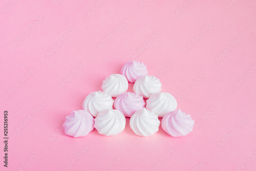 white and pink twisted meringues in a shape of pyramid on pink background, greeting card, copy space