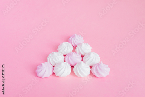 white and pink twisted meringues in a shape of pyramid on pink background, greeting card, copy space