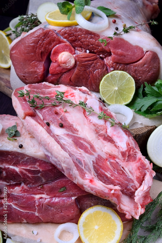 Raw pork, beef and mutton surrounded by herbs, spices and lime slices