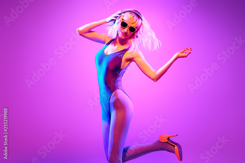 Fashion. Glamour party fitness woman enjoy nightlife. Sexy carefree DJ girl in colorful neon light having fun. Beautiful fashionable blonde model smiling dance. Creative, Funny positive emotion